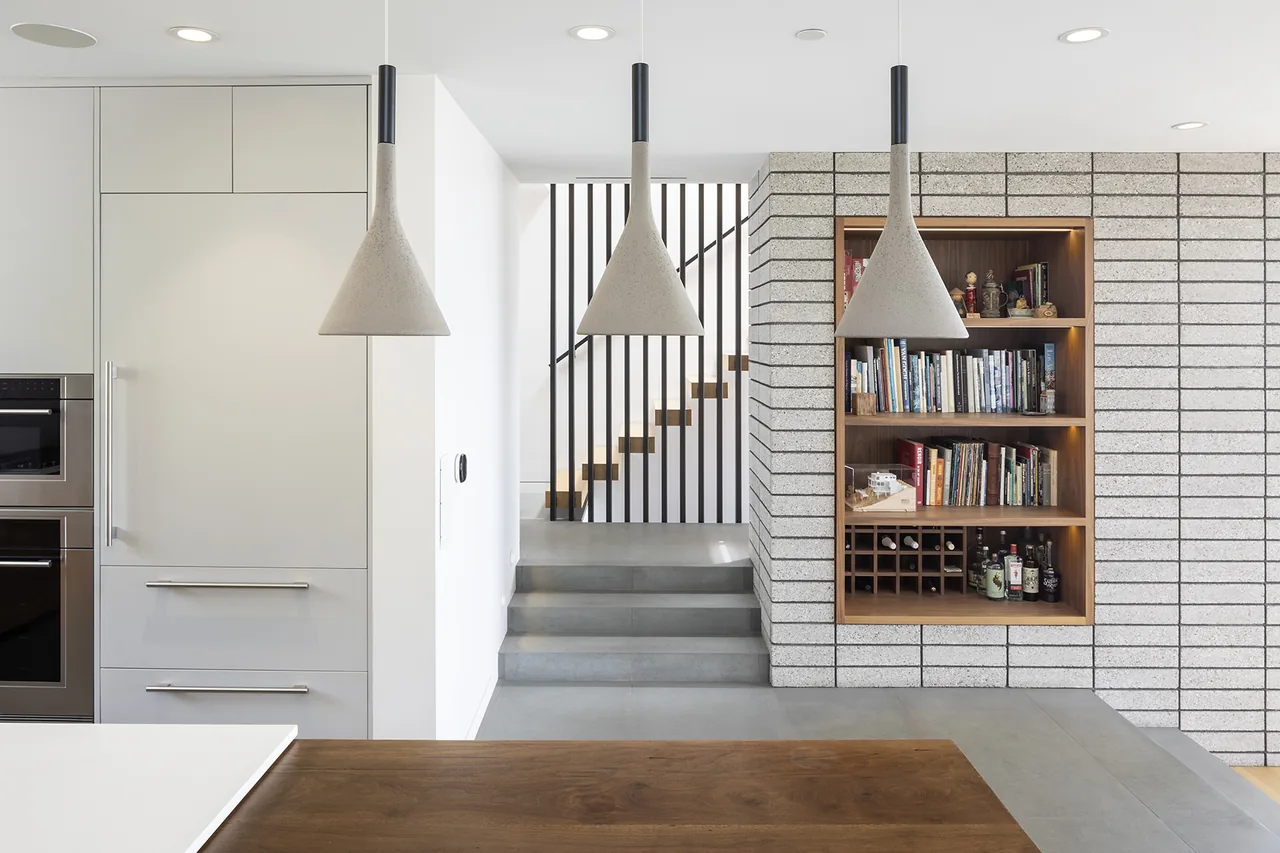 Palisades House kitchen with concrete tile floor and floating open riser stairs by Rob Paulus Architects.