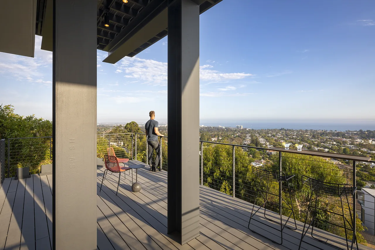 Deck of Palisades House features metal columns and wire railing with panoramic city and ocean views.