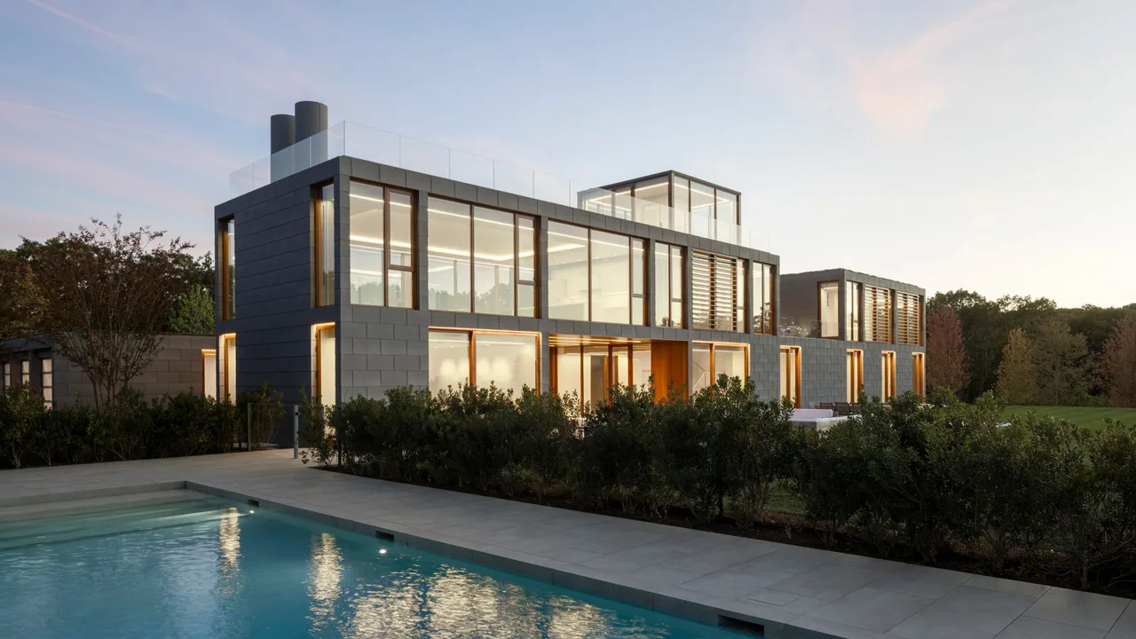Fairway House features modern architecture with large windows, glass balustrades, and metal panel cladding, shown here at dusk with a pool in foreground.