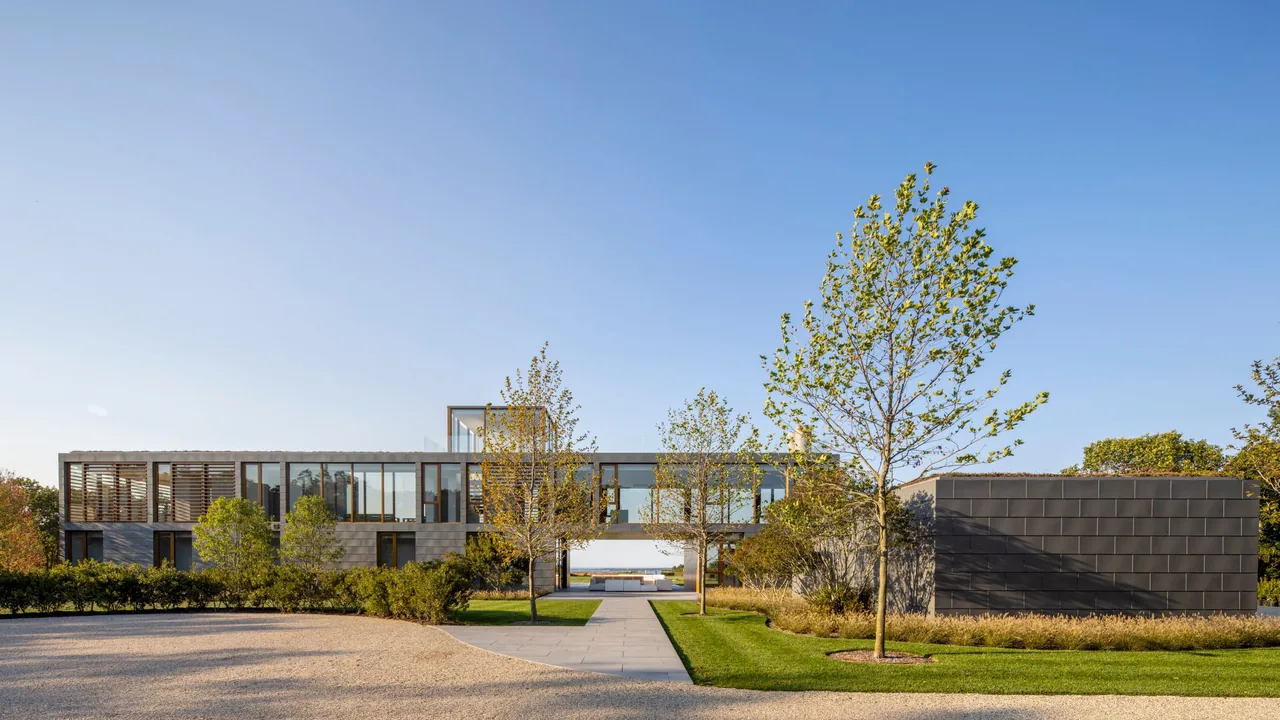 Fairway House by Roger Ferris + Partners shows metal panel cladding, large glass windows, and wooden louvers in a modern architectural style.