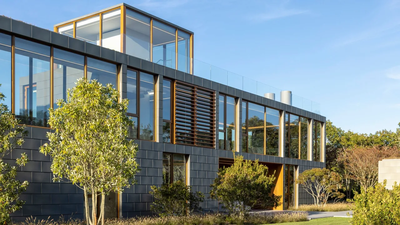 Fairway House features dark metal panel cladding, extensive floor-to-ceiling glazing, and horizontal wooden louvers with a glass balustrade on the upper terrace.