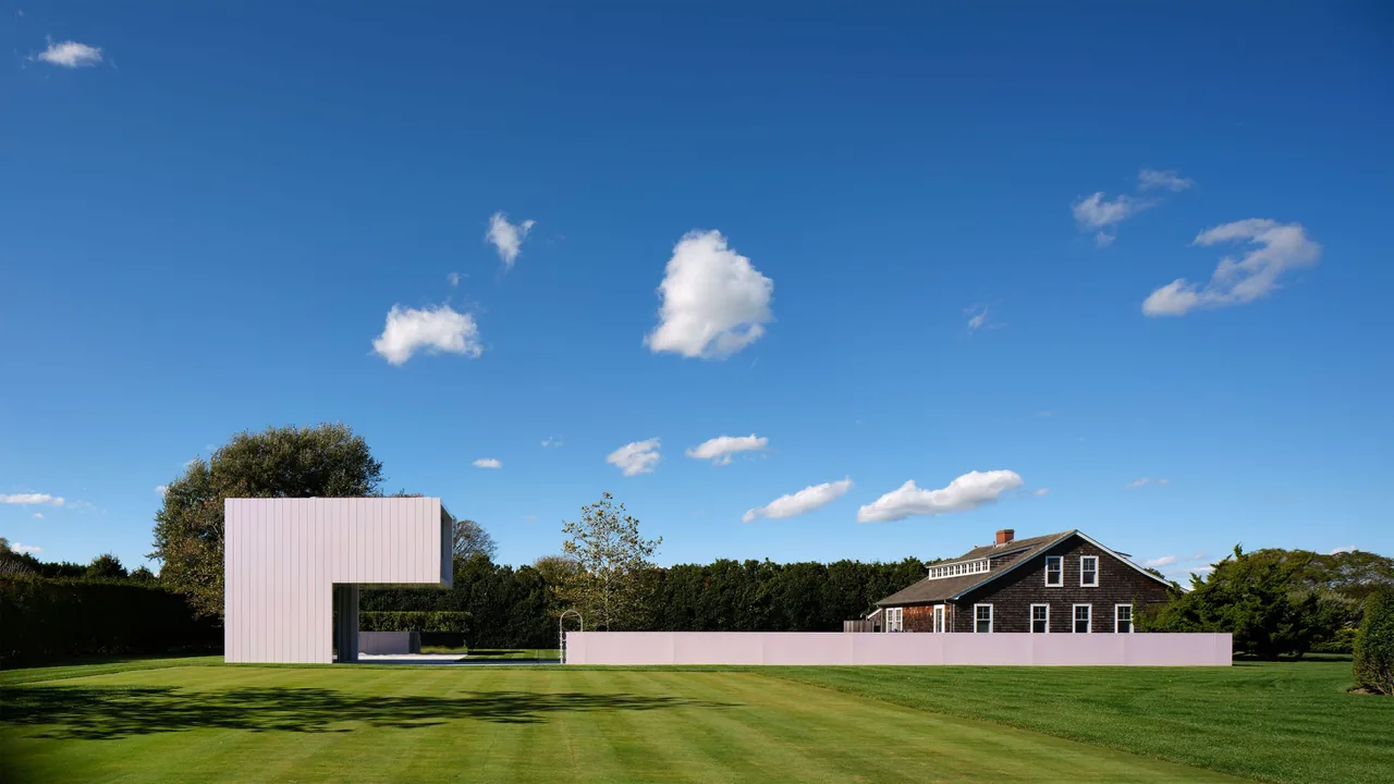 The Pink House project features a minimalist rectangular volume with a pink fence, contrasting a traditional house nearby.