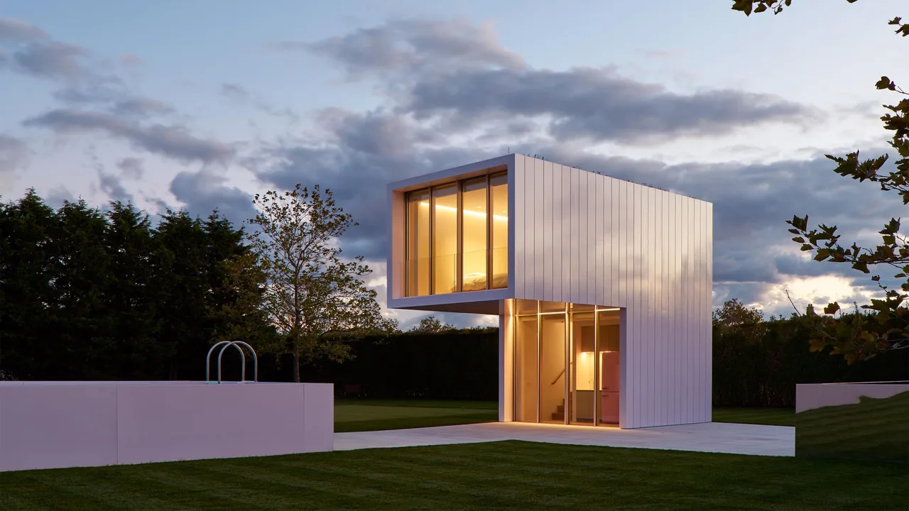 The Pink House pool house features a minimalist rectangular volume with pink exterior and floor-to-ceiling glazing.
