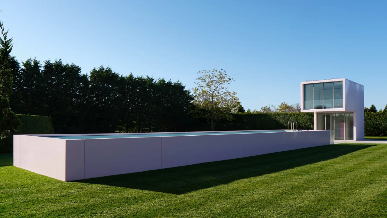 The Pink House features a minimalist rectangular pink pool structure with a glass balcony above a paved patio area.