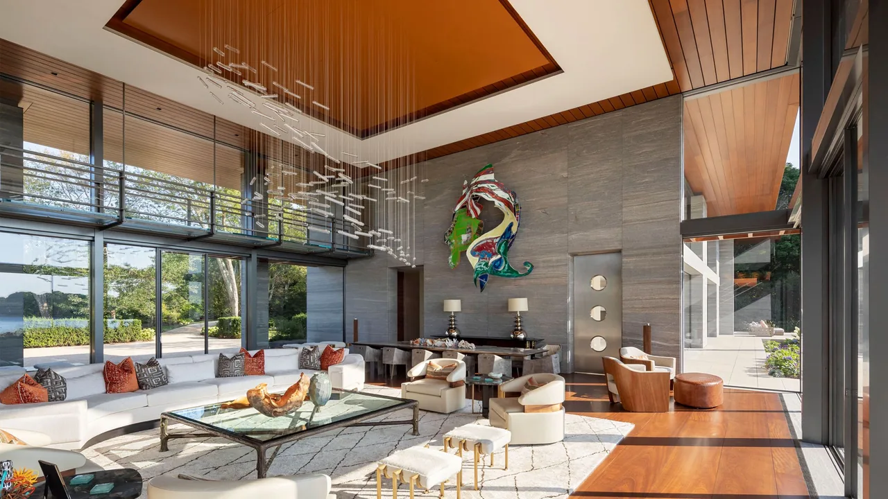 Living room of the Millstone project features floor-to-ceiling glazing and a curved white sofa with colorful pillows.