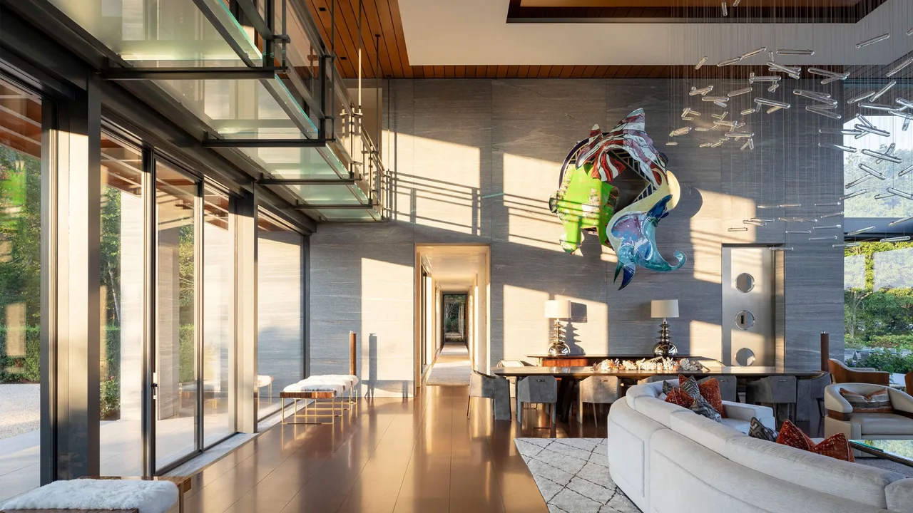 Living and dining rooms with floor-to-ceiling glass walls, wood flooring, and colorful wall art at Millstone project.