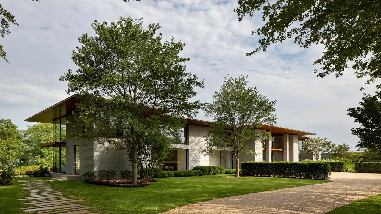 The Millstone project features a flat roof with deep overhangs and extensive glazing surrounded by trees and manicured lawn.