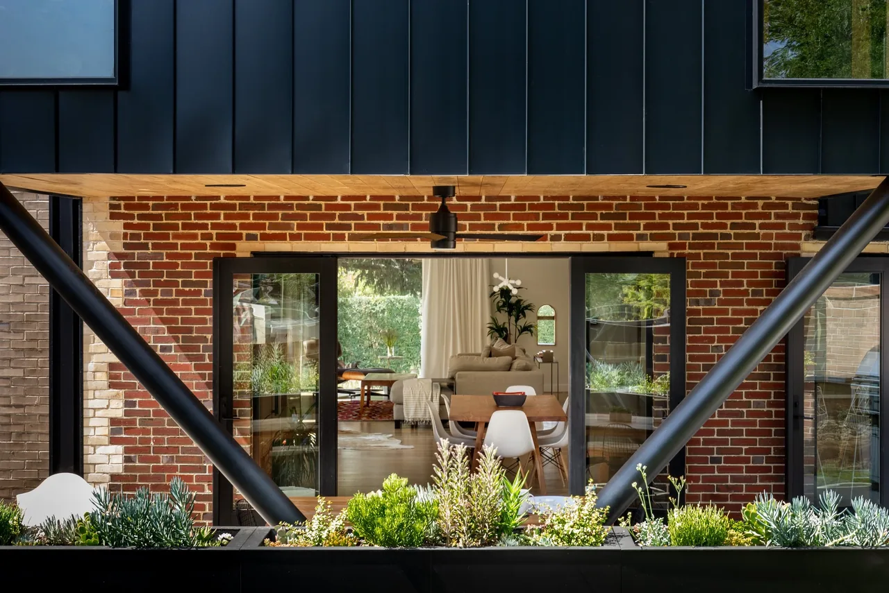 The Rabbit House features black window frames and a mixed brick and metal façade with a dining area visible through glass doors.
