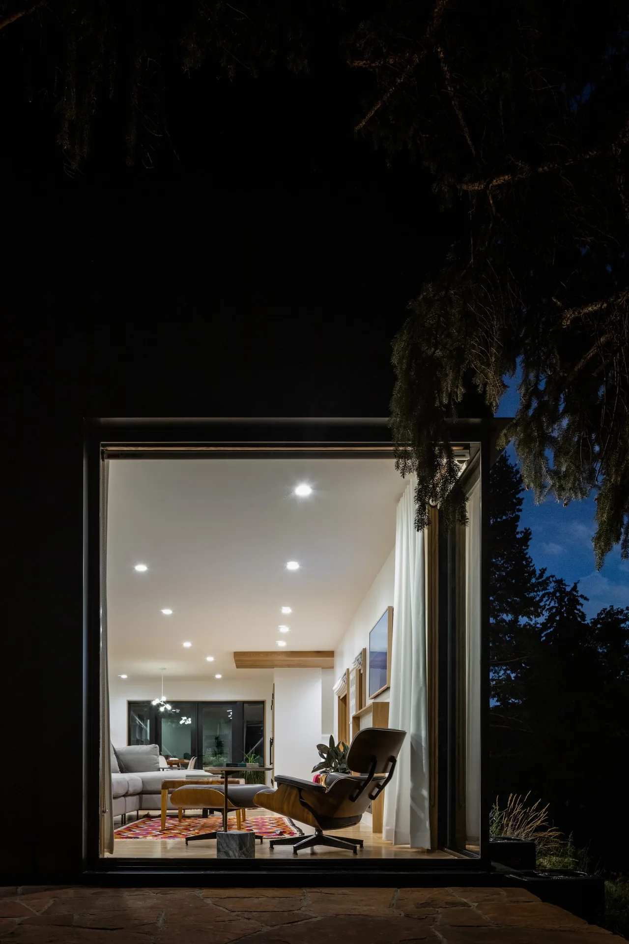 Night view of the Rabbit House living room features modern furnishings and recessed ceiling lights.