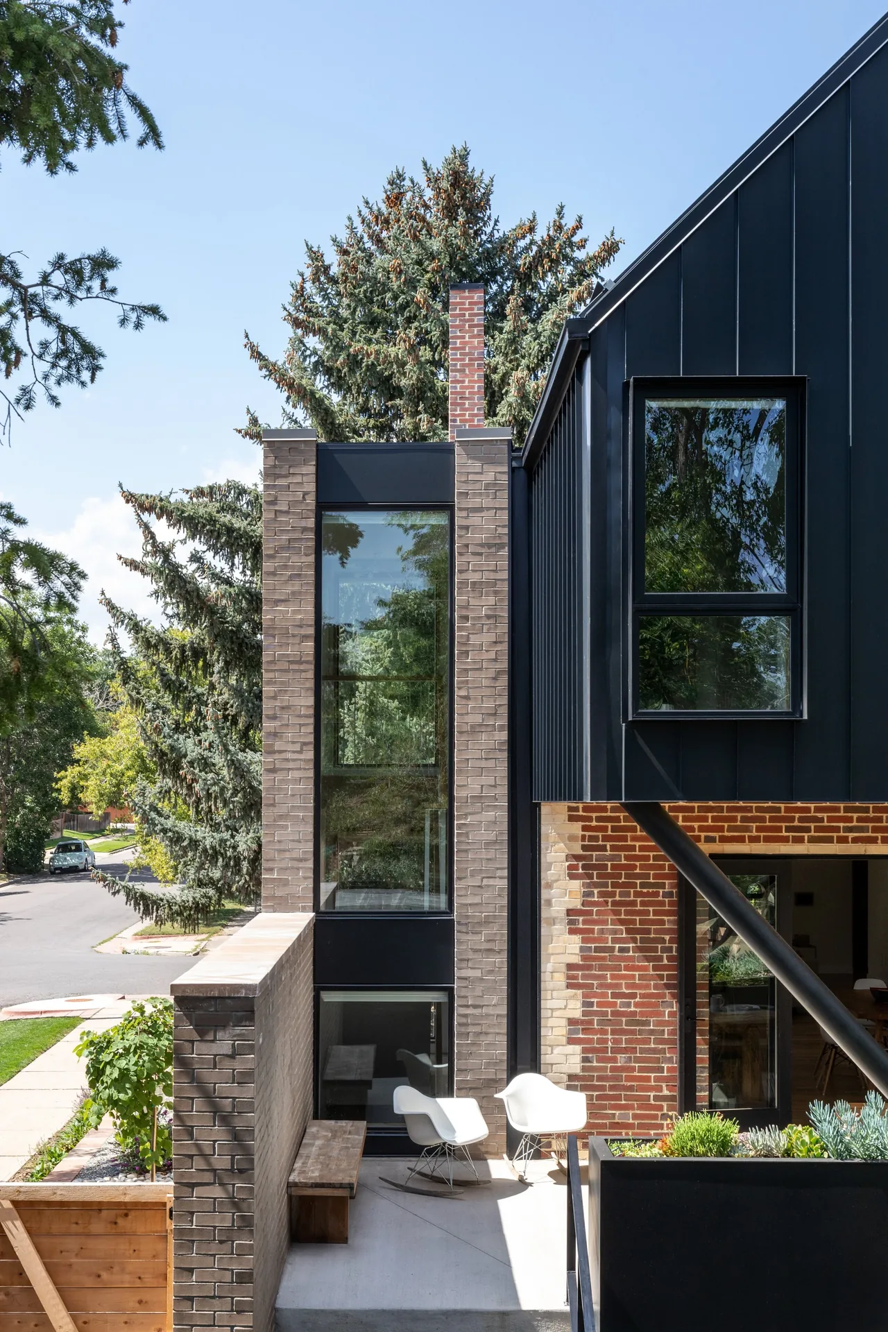 The Rabbit House features brick and black metal siding with large windows and an exterior patio area with seating.