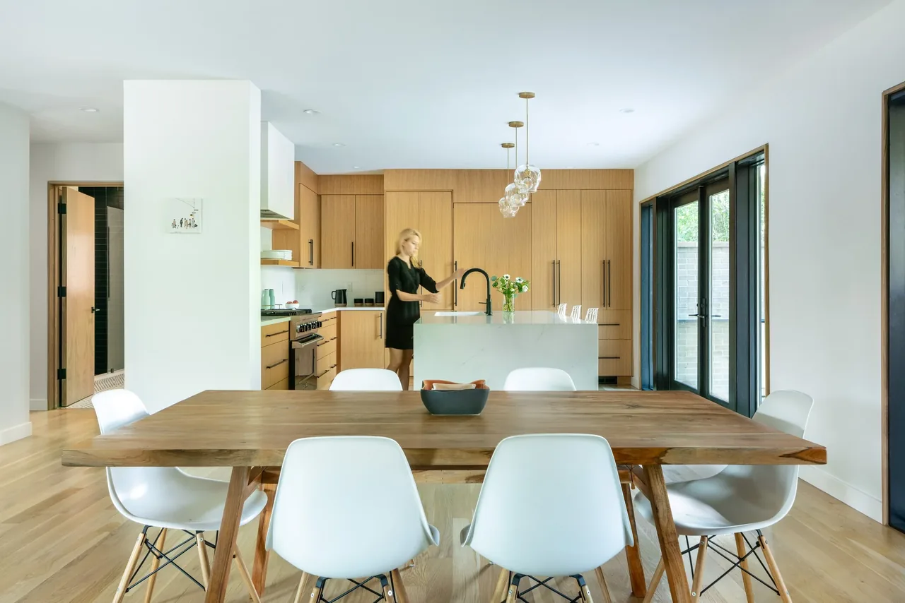Inside the Rabbit House kitchen and dining area featuring light wood cabinetry, a wooden dining table, and black-framed sliding glass doors.