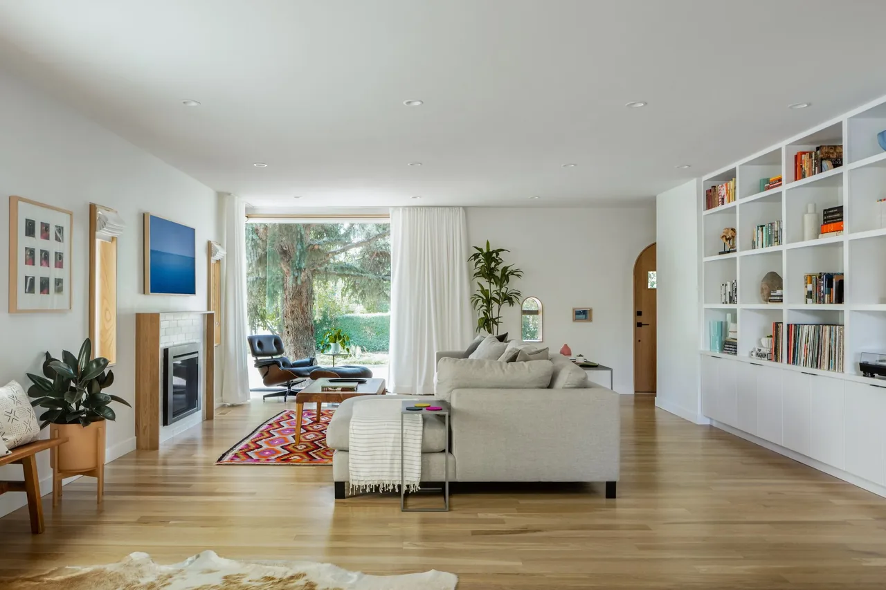 Rabbit House living room with floor-to-ceiling window, sectional sofa, fireplace, and extensive built-in white shelves.