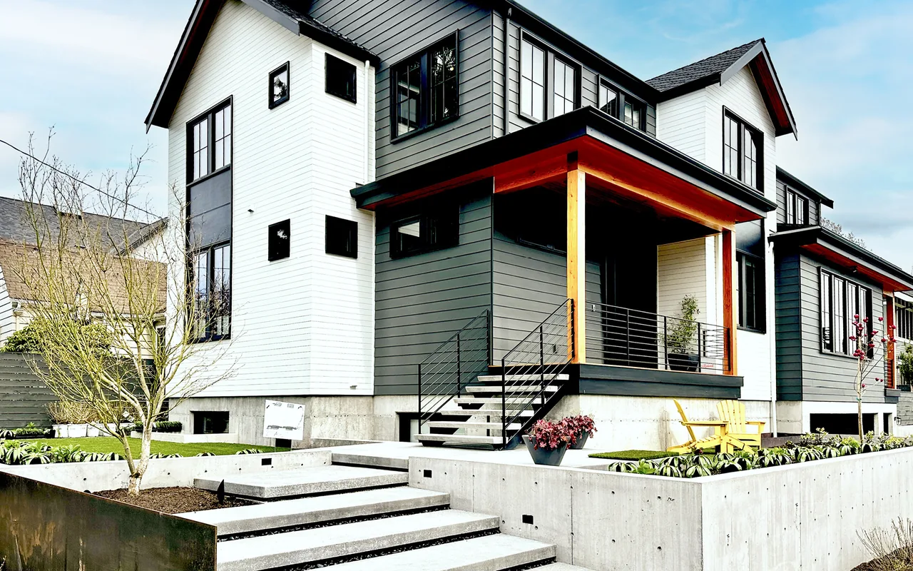 Contemporary home with mixed siding colors, concrete steps, and a covered porch featuring black metal railing.