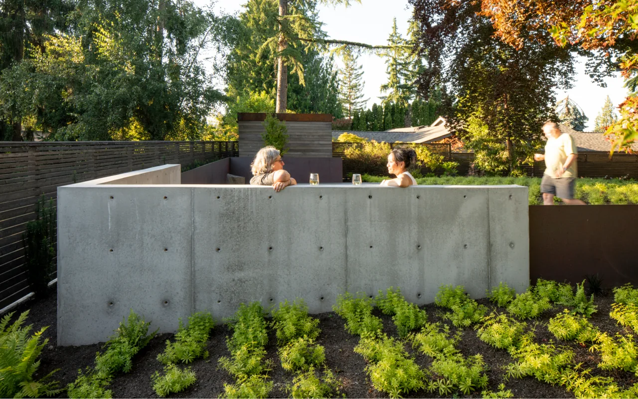 A concrete wall encloses a private seating area in the backyard of the Bellevue Split-Level project.