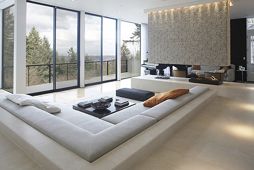 Wei Residence features a built-in banquette surrounding a sunken living area with a stone fireplace and expansive glazing.