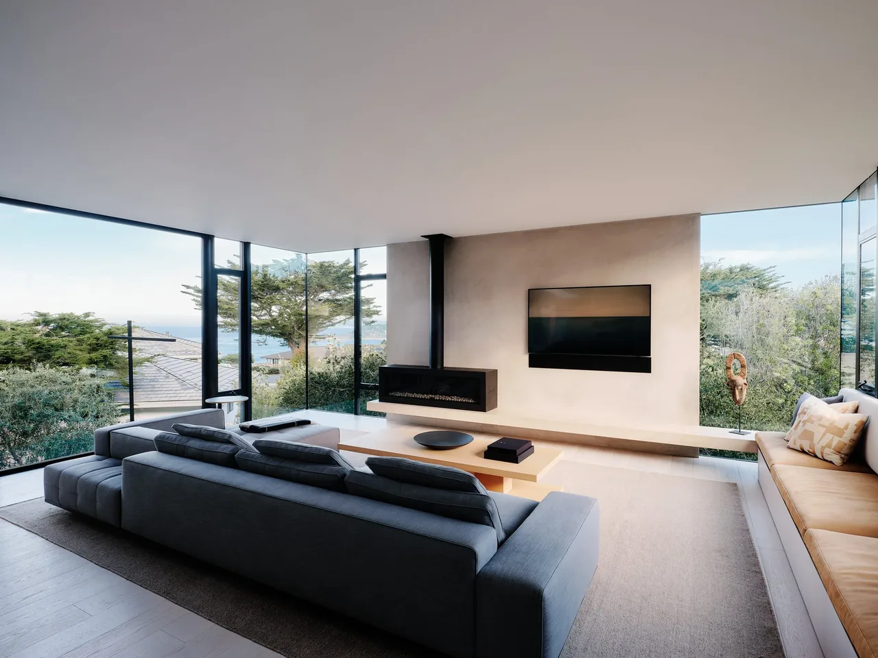 Living room with large floor-to-ceiling windows, a floating fireplace, and built-in seating at Carmel Meadows project.