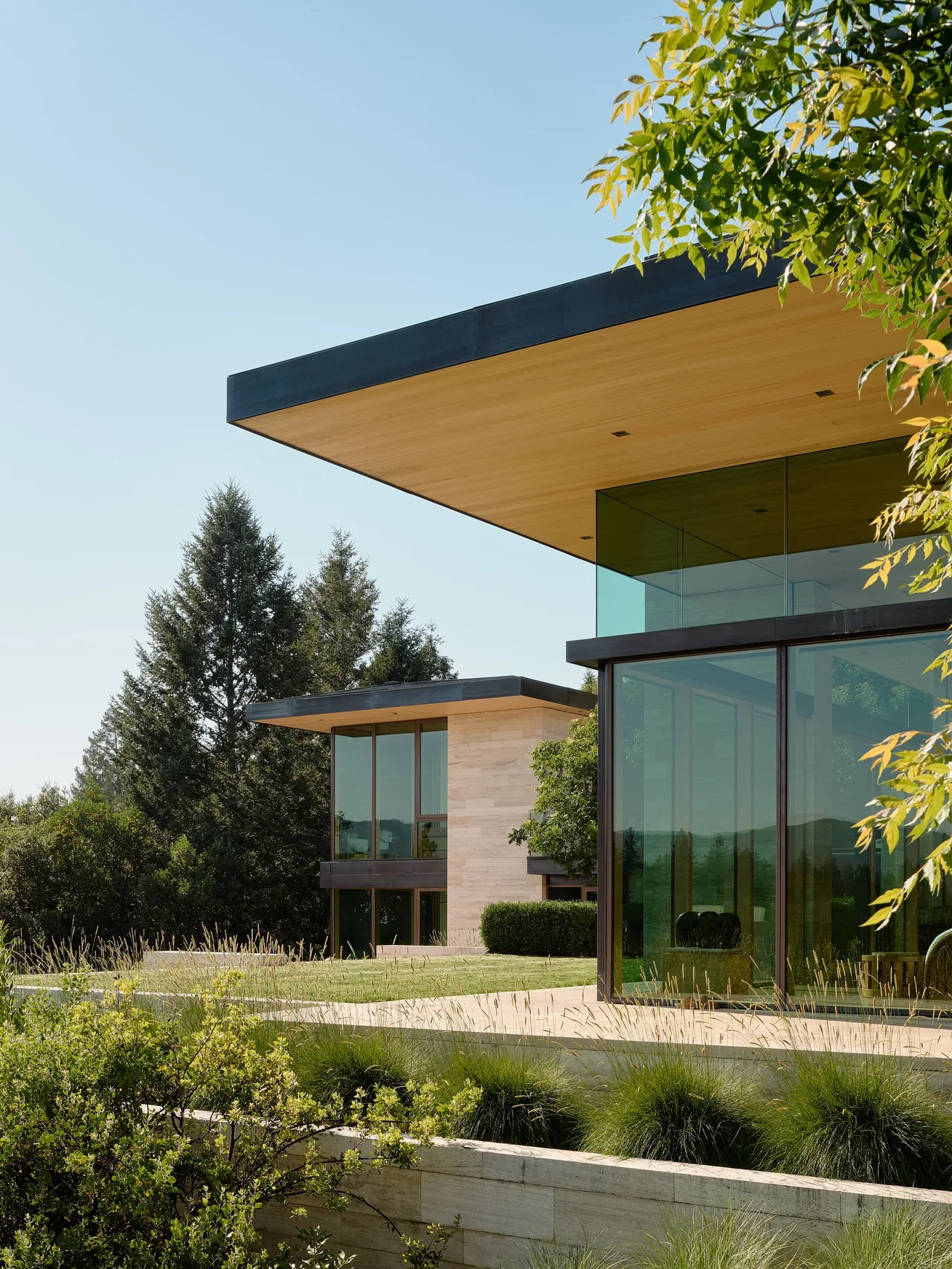 Modern home exterior showing flat roof with wood soffit and extensive floor-to-ceiling glazing