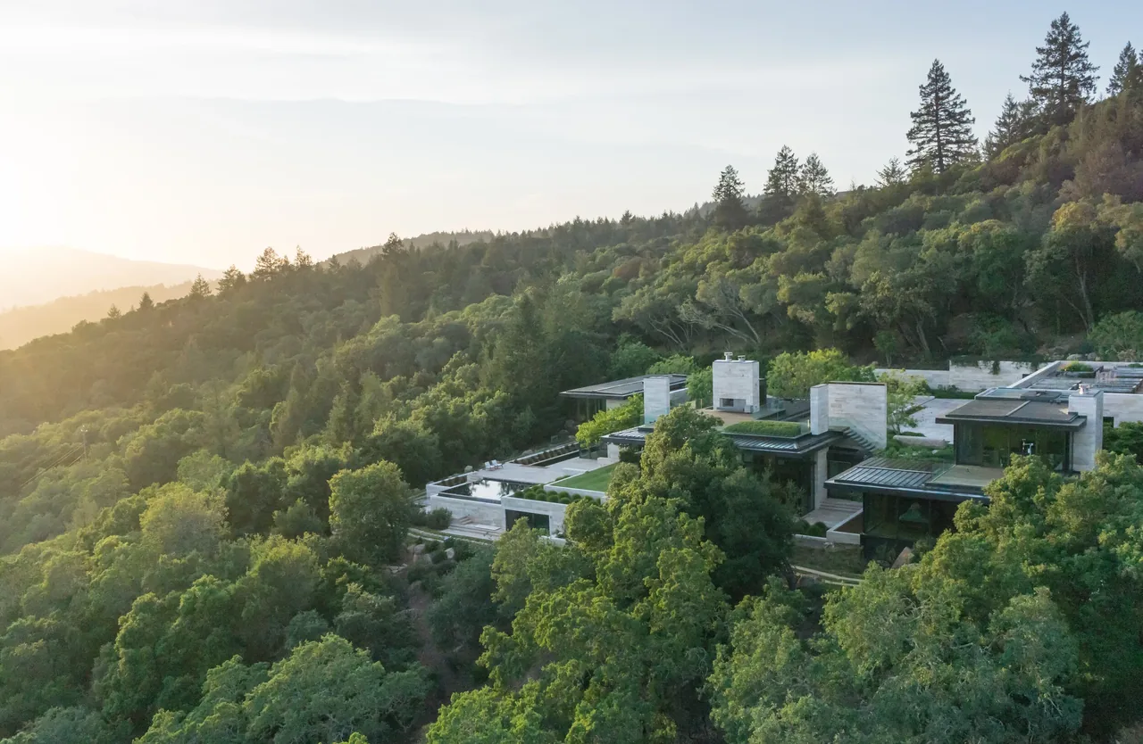 The St Helena residence by Sagan Piechota Architecture features modern flat roofs and outdoor living spaces nestled in lush forested hillside.