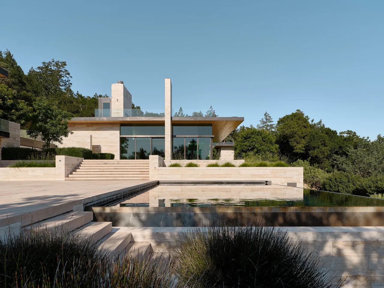 Exterior front of St Helena residence featuring stone steps, a reflecting pool, and a wood soffit under a flat roof.