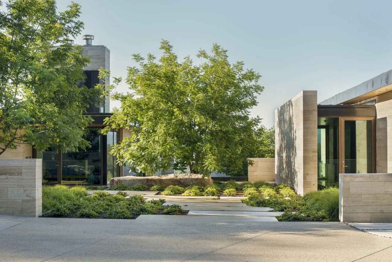 Front exterior of the St Helena project with stone walls, landscaped greenery, and modern architectural features.