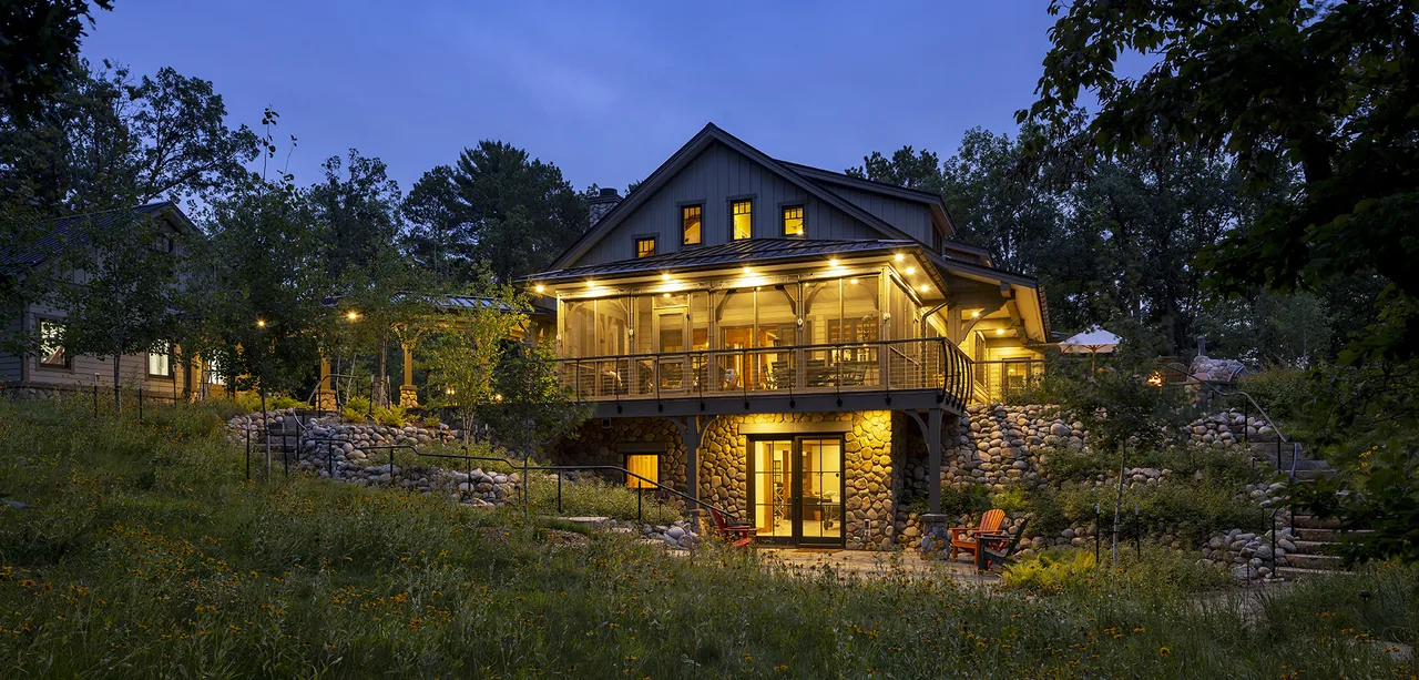 Tall Tree Lodge features a stone foundation, wood siding, and a screened porch overlooking a terraced yard with seating areas.