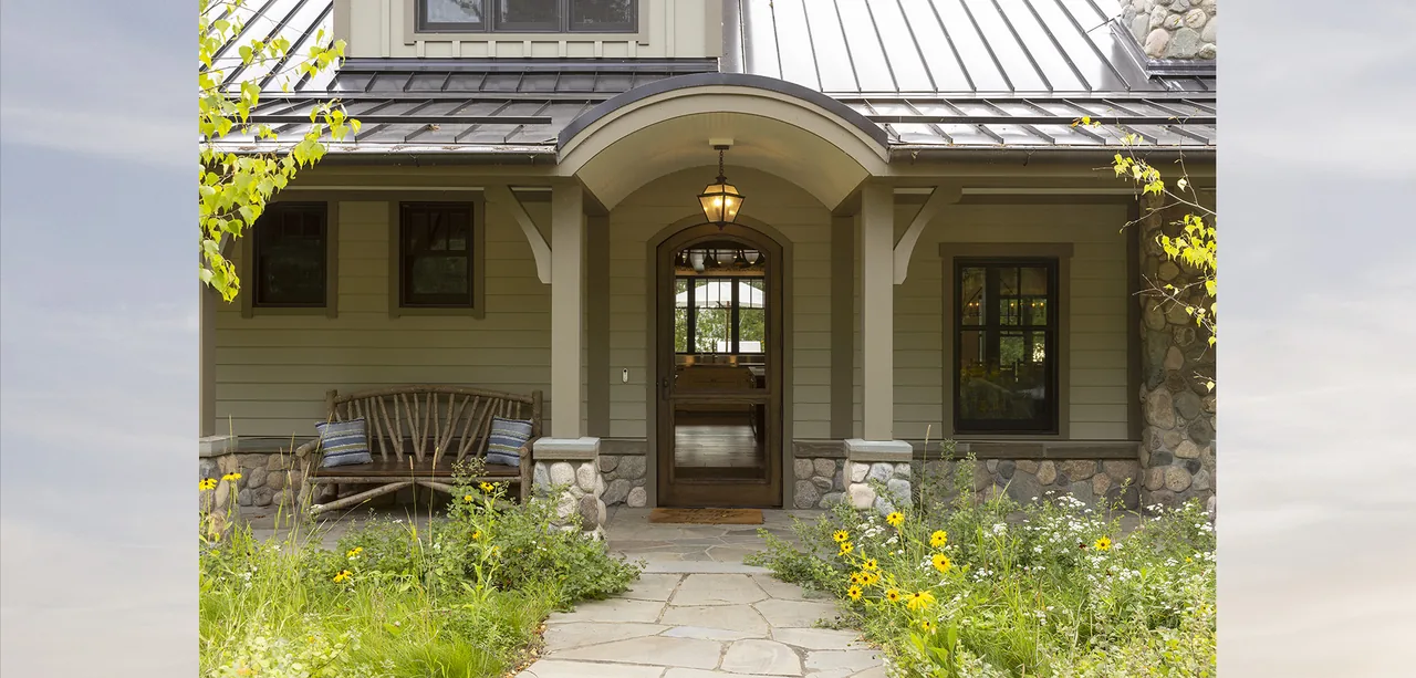 The Tall Tree Lodge front porch features stone foundations and an arched roof with a wooden bench seating area.