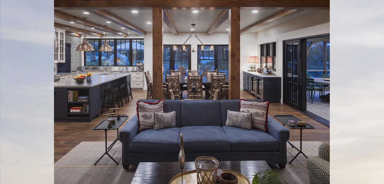 Living room with blue sofa opens to a kitchen with island and dining area in Tall Tree Lodge.