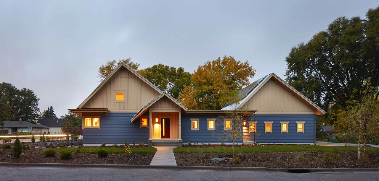 Ohm Sweet Ohm project by SALA Architects showcases a modern farmhouse with blue wood siding and beige board and batten accents.