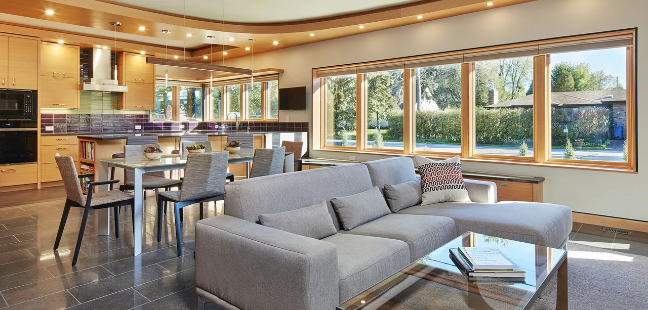 Open living and kitchen space with a purple tile backsplash and multiple small windows providing street views.