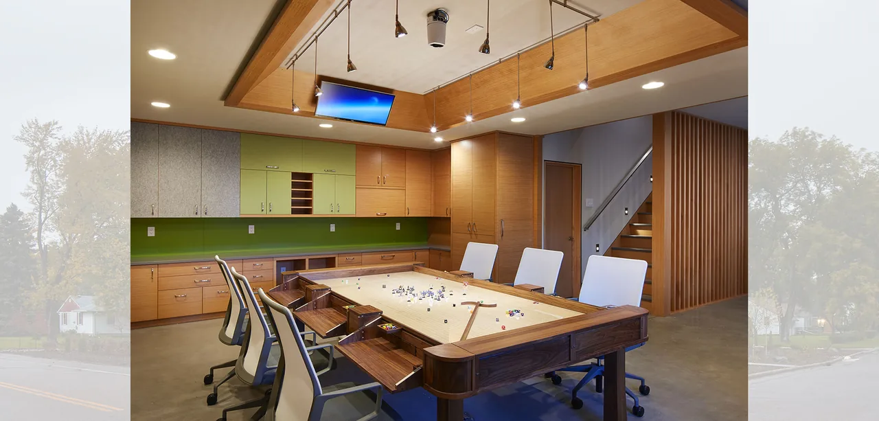 Game room in Ohm Sweet Ohm with custom wood game table, green accent wall, and wood cabinetry by SALA Architects.