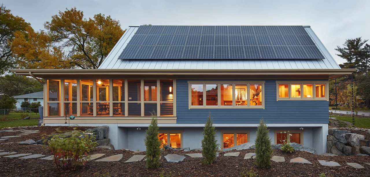 Two-story home with a standing seam metal roof featuring solar panels and blue board and batten siding.