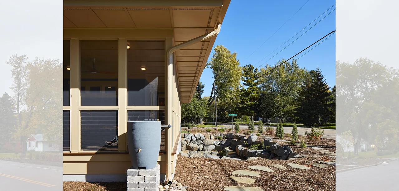 Beige house exterior with vertical windows and a landscaped rock garden with stepping stones.