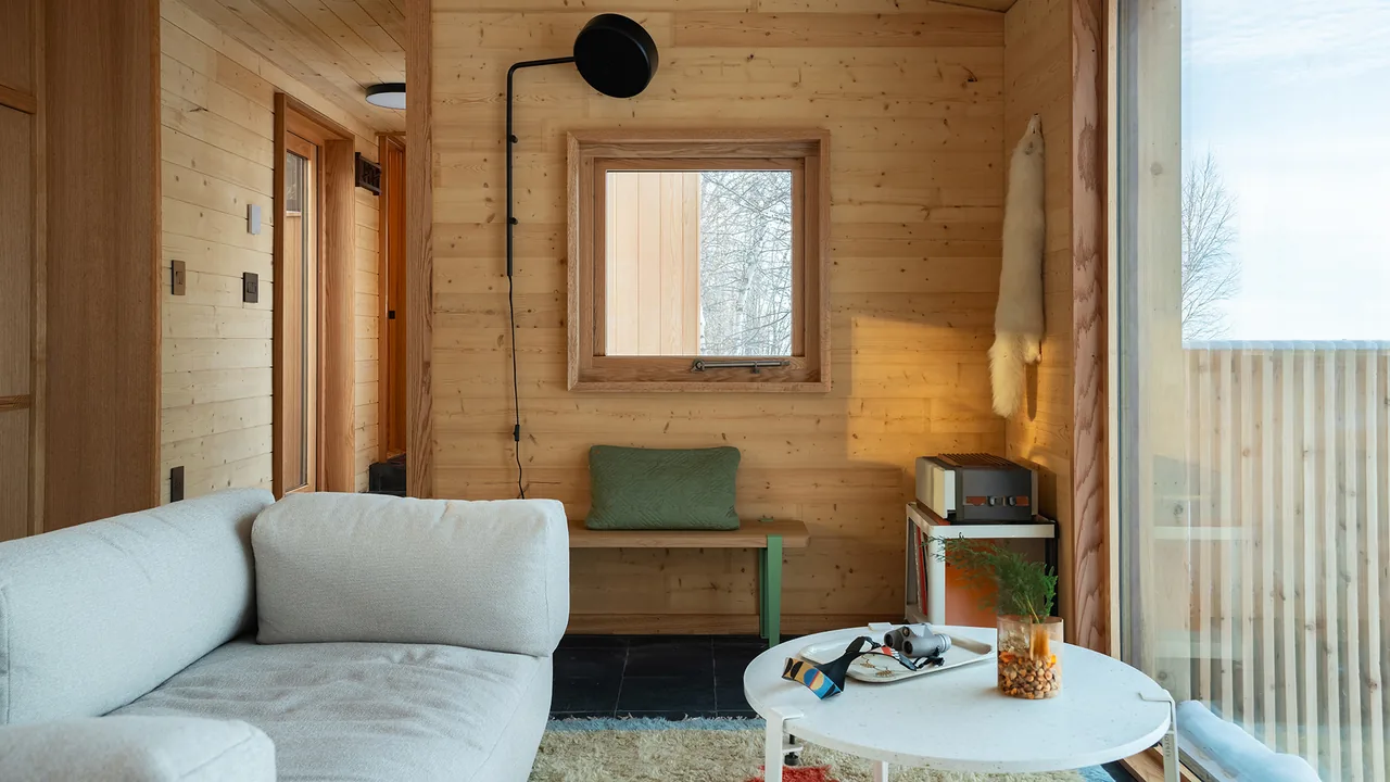 Living room in Warroad CLT House features wood panel walls, a white sofa, and large windows providing natural light and outdoor views.