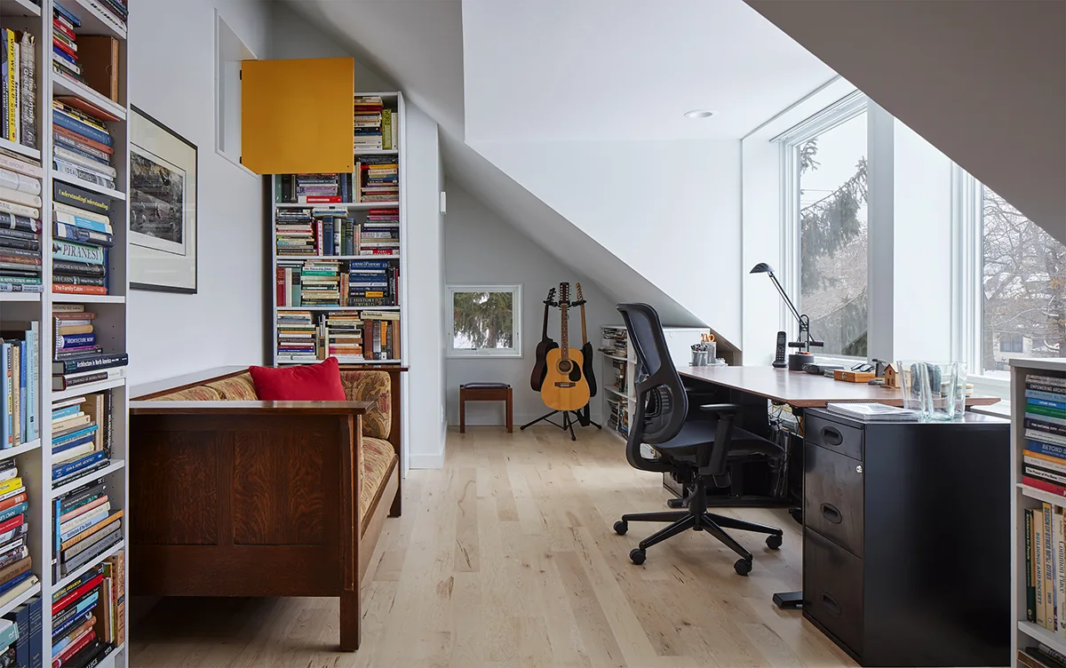 This home office features large vertical windows and built-in bookshelves under a slanted ceiling.