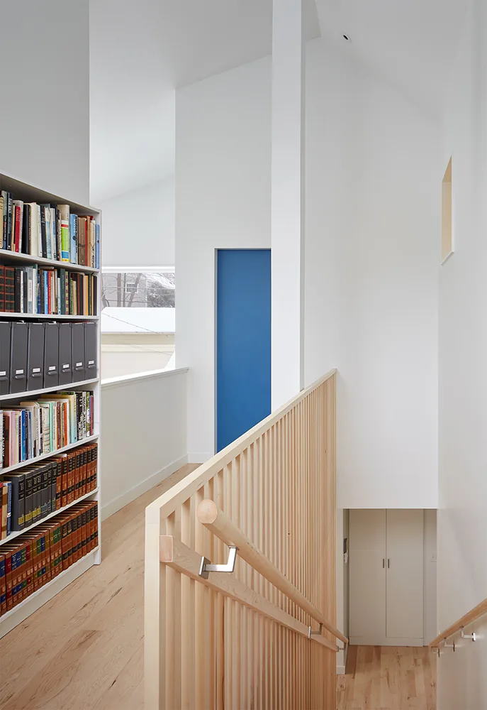 The staircase features vertical wood slats and leads to a landing with a blue door.