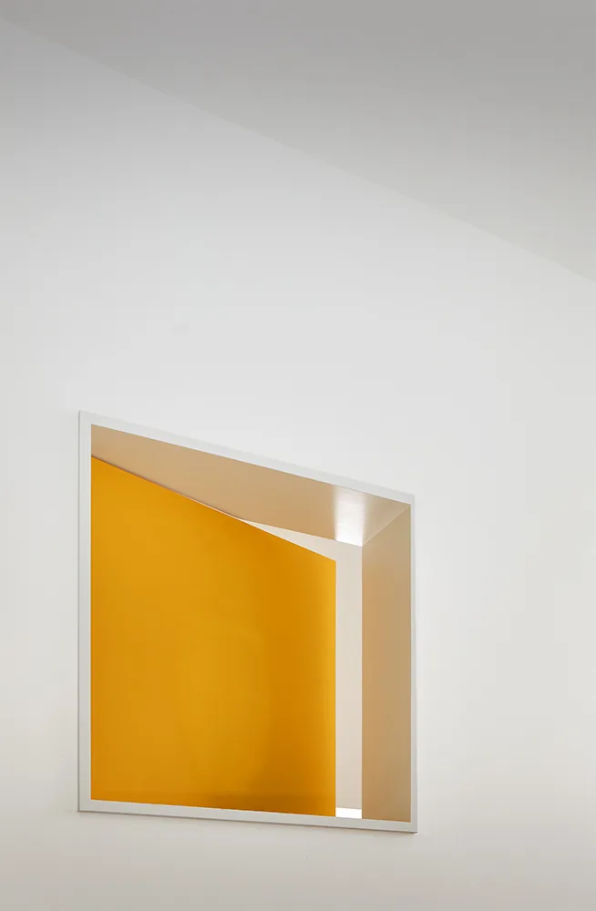 Mirror reflects interior with yellow wall and slanted ceiling in a modern-style space.