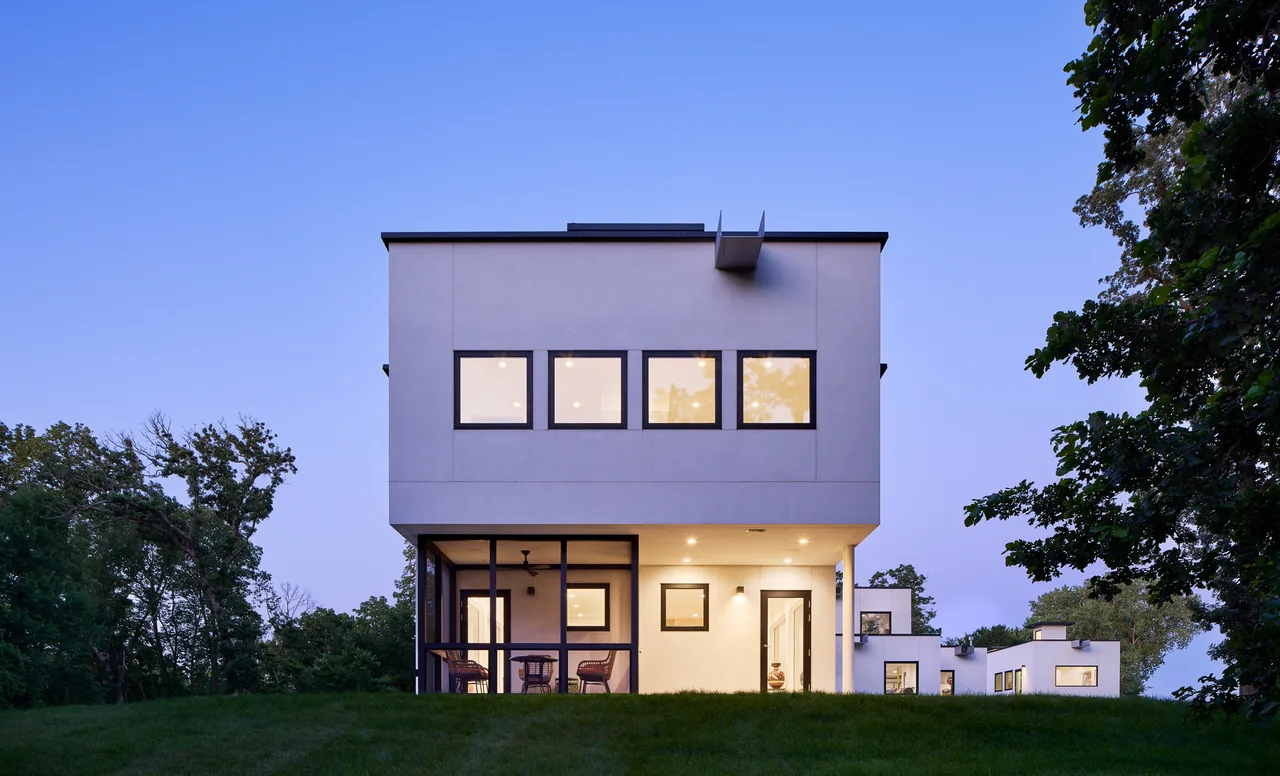 The Bauhaus Farm features cubic volumes with flat roofs and black window frames in a minimalist farmhouse style.