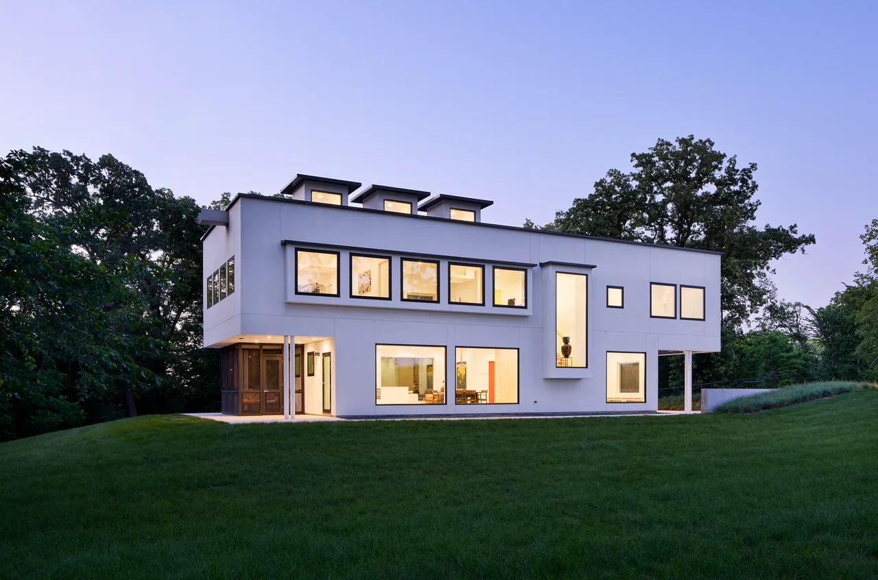 The Bauhaus Farm project features a minimalist cubic volume farmhouse with large windows and a flat roof.