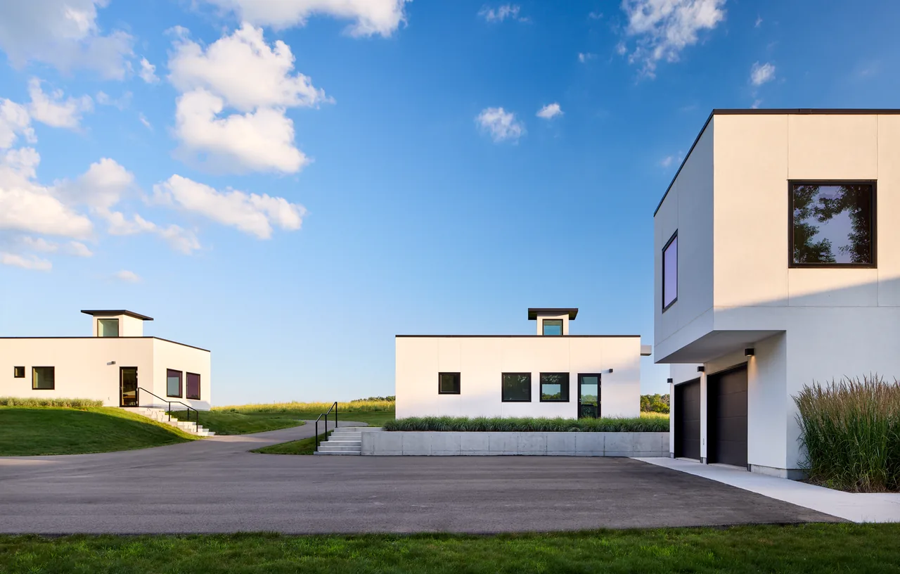 The Bauhaus Farm features minimalist cubic buildings with white exteriors and black window frames.