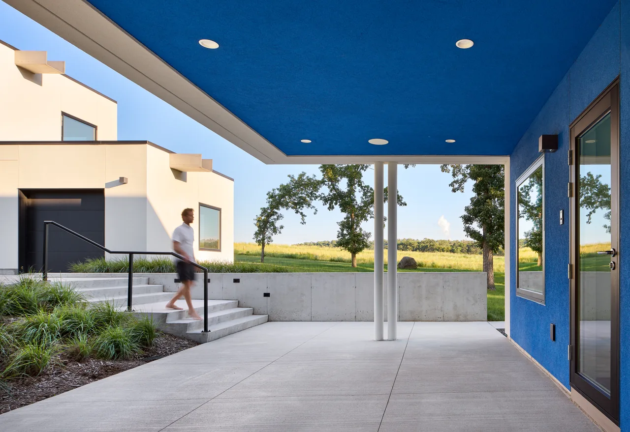 Bauhaus Farm features modern cubic buildings and a blue ceiling patio amid a grassy field.