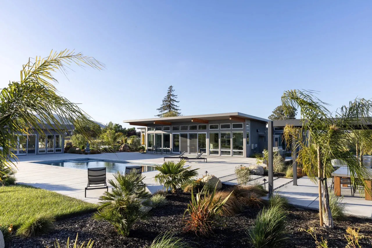 A flat-roof pavilion house in Sonoma with large glass doors opening to a pool and landscaped garden.