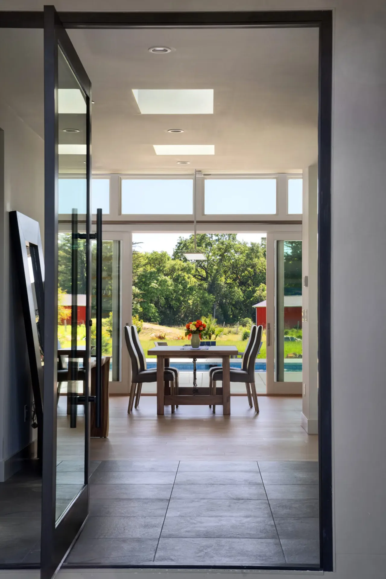 Dining room with skylights and large glass doors opening to a pool and garden in Sonoma project.