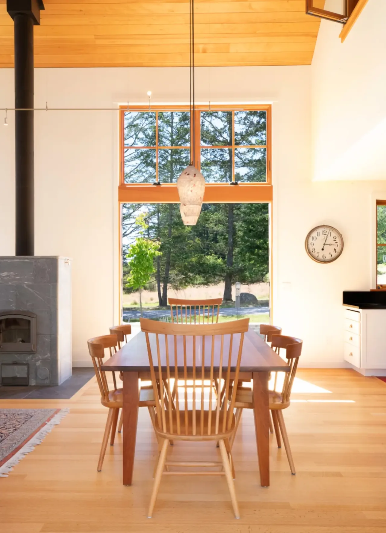 Dining room with wooden furniture, large multi-pane window, and a pendant light hanging over the table.