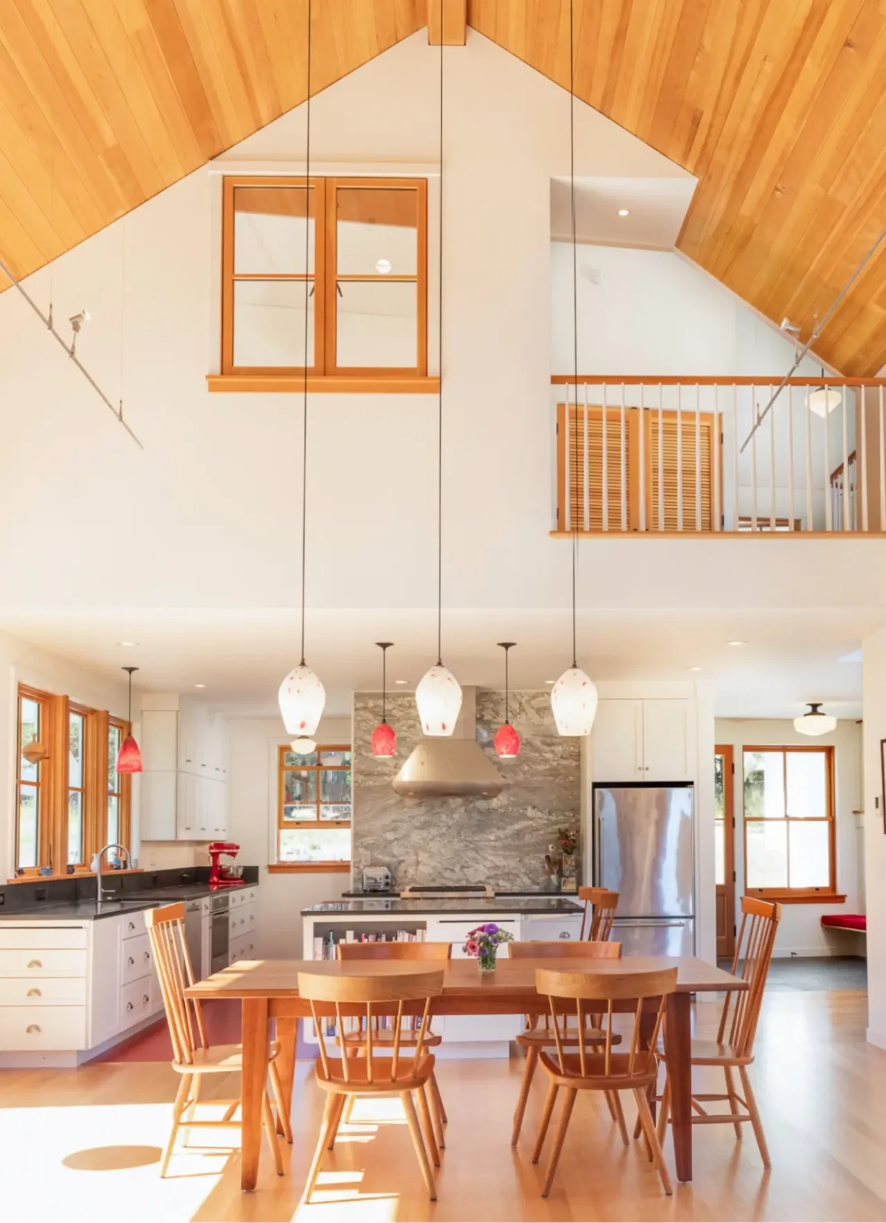 MAP CORNER kitchen and dining area features a vaulted wood ceiling with pendant lighting and a marble backsplash behind the stove.