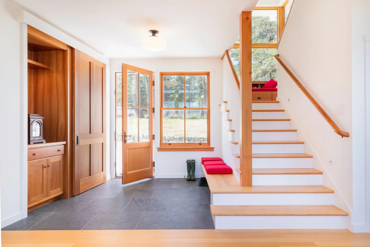 Entryway features a wooden door and window, black tiled flooring, and a staircase with light wood treads and handrail.