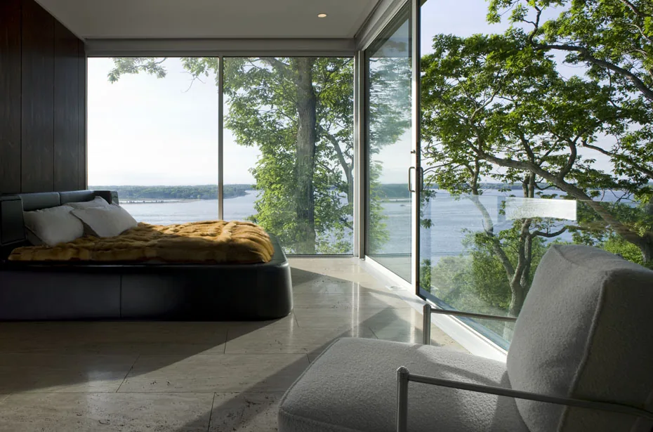 The Clearhouse bedroom features floor-to-ceiling glazing to capture scenic water and tree views.