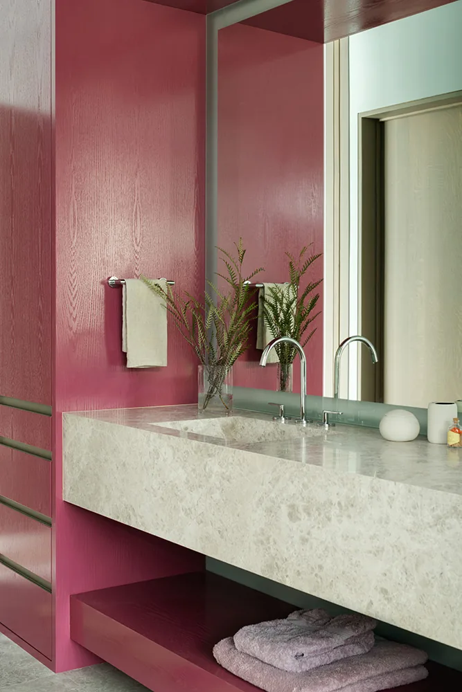 Bathroom features a marble countertop sink and fuchsia wood-paneled walls and cabinetry.