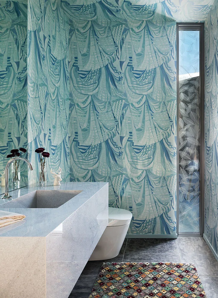 Bathroom featuring blue abstract patterned wallpaper and a narrow vertical frosted window beside the toilet.