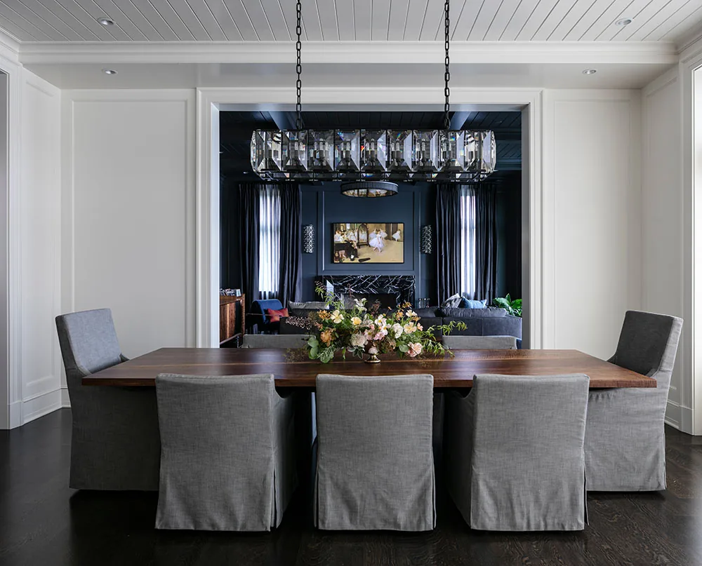Dining room features a dark wood table with six gray upholstered chairs and a rectangular crystal chandelier.