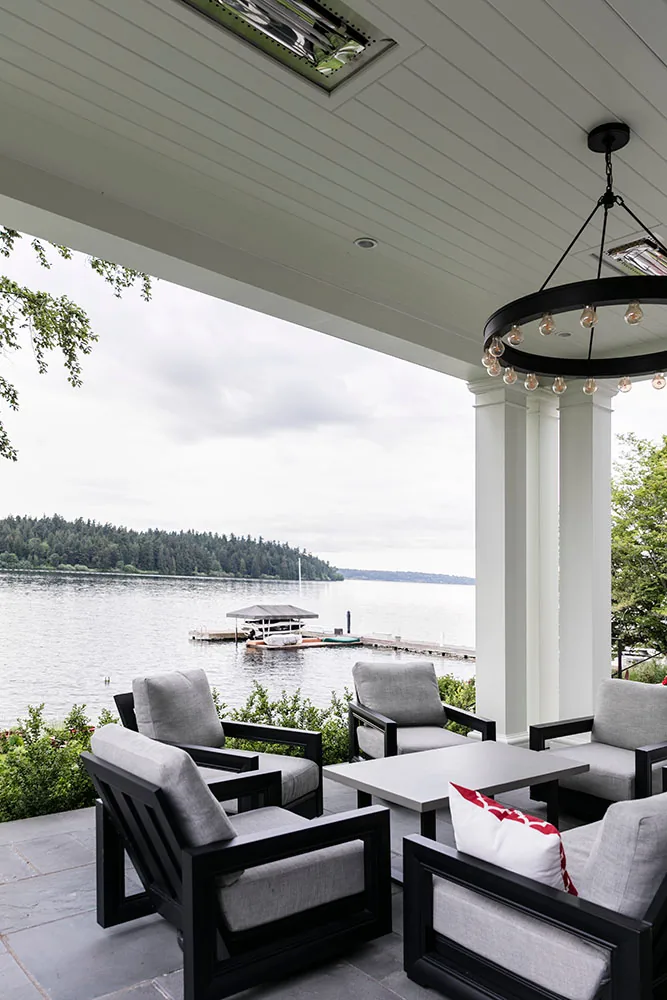 Covered patio with seating and a view of the lake and dock at the residence in Seattle.